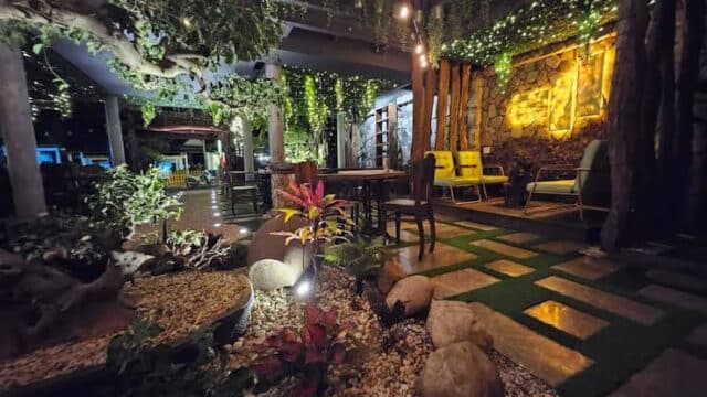 Cozy Hoi An outdoor cafe with string lights, plants, stone path, and wooden furniture creating a warm ambiance.
