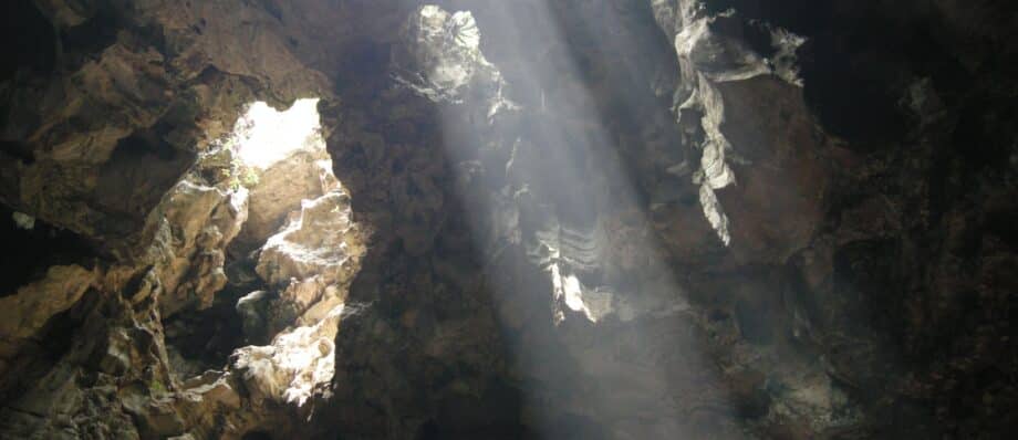 Sunlight streaming through the roof of Huyen Khong cave onto Buddhist statues, Marble Mountains