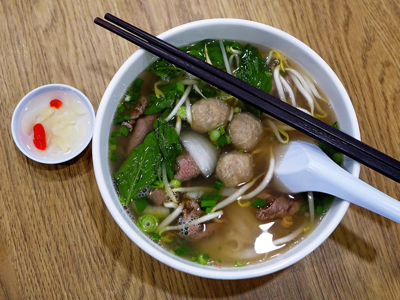 Pho bowl with bean sprouts, herbs and chopsticks