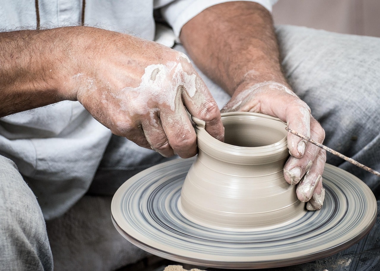 Potters hands shaping a clay cup on the wheel
