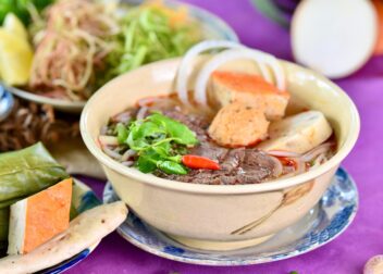 A bowl of beef pho with noodles and herbs