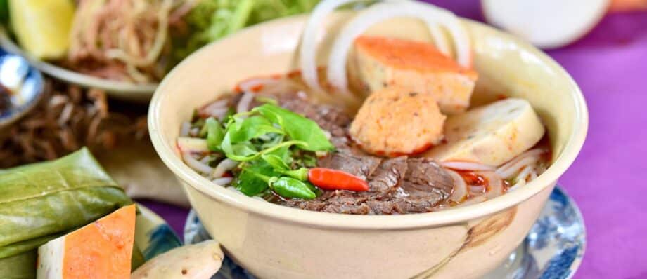 A bowl of beef pho with noodles and herbs