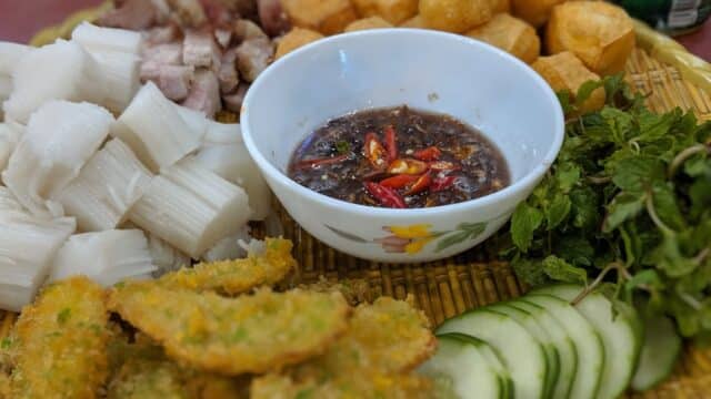 A Hoi An-inspired platter with rice noodles, fried tofu, pork, fresh herbs, cucumber, and chili dipping sauce.
