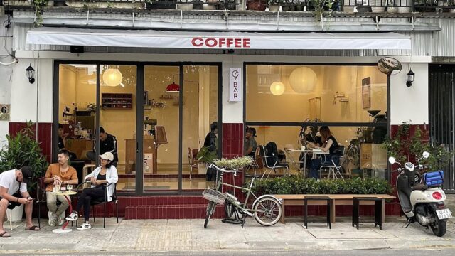 Street view of a cozy Hoi An coffee shop with people sitting outside and bikes parked in front.