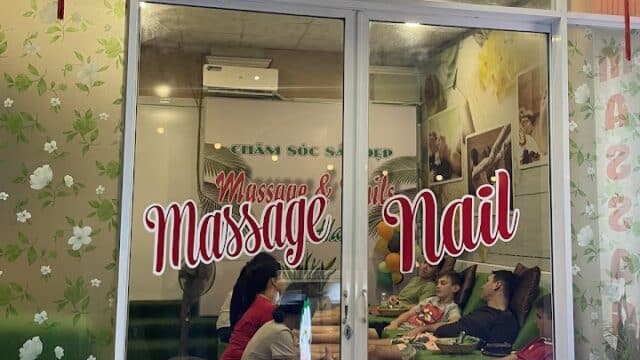 Glass storefront of A.HAO Massage & Nail salon with people seated inside, red lanterns hanging above the entrance.