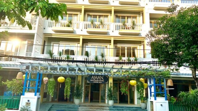 Aman-inspired boutique hotel with balconies, potted plants, and a glass awning welcomes you at the entrance.