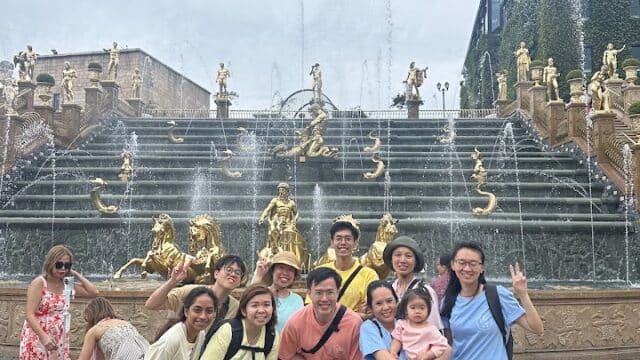 A group of people poses, smiling, in front of a golden fountain during their Hoi An Private Tours adventure.