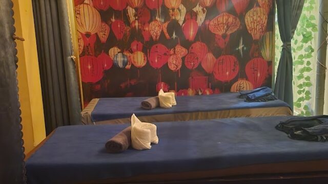 Three massage beds with rolled towels in a spa, lantern mural and relaxing spa images on the wall.