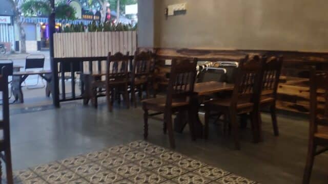 Cozy Hoi An cafe with wooden chairs, patterned floor tiles, and vintage posters on a gray wall.