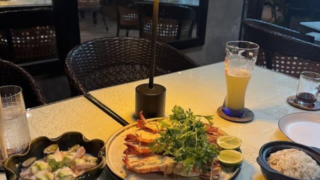 A table with grilled seafood, rice, and ceviche at Citadel Restaurant & Bar, a cozy, dimly lit spot where people enjoy dining.