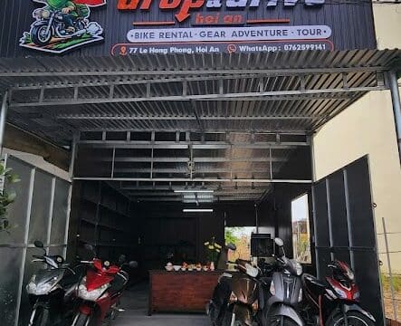 Front view of a motorbike rental shop with drop and drive service; multiple motorcycles parked outside under a metal roof.