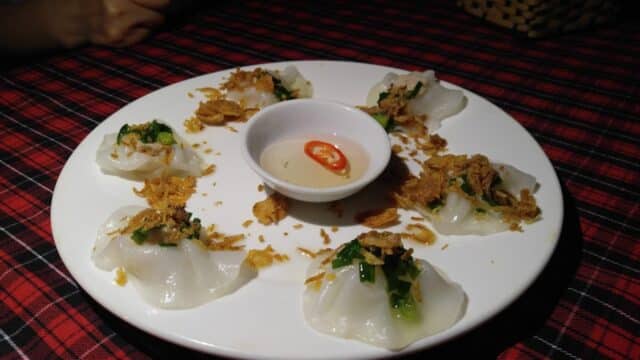 Six steamed dumplings with crispy toppings surround a dipping sauce, just like at Floating Boat Restaurant.