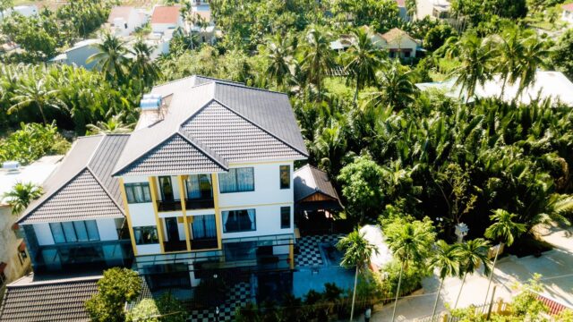 Modern Flower Villa with a tiled roof surrounded by lush palm trees and greenery in a tropical setting.