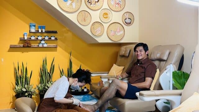 A man gets a pedicure at a salon with yellow walls, decorative signs, and relaxing treatments at G360 Foot Spa.