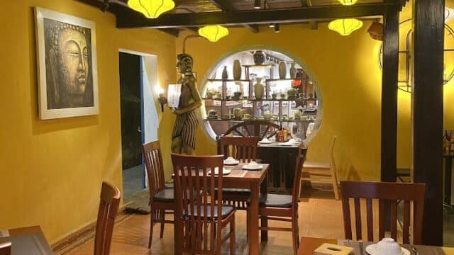 Cozy restaurant with yellow lanterns, wooden tables, and a Buddha painting on a yellow wall welcomes you to the Golden Dragon.