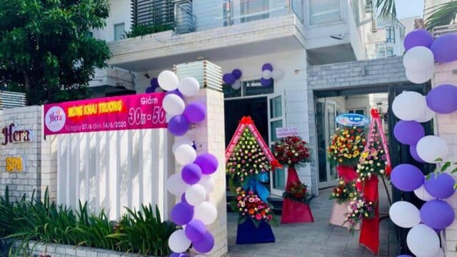 Hera Spa storefront decorated with purple and white balloons, banners, and flower stands for a Beauty opening event.