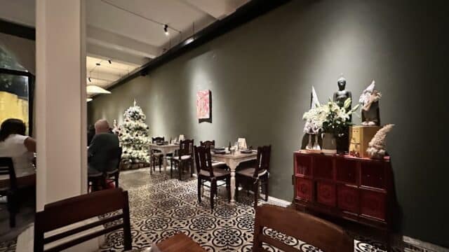 Cozy Hoi An restaurant with a Christmas tree, Buddha statue, and elegant decor along a green wall.
