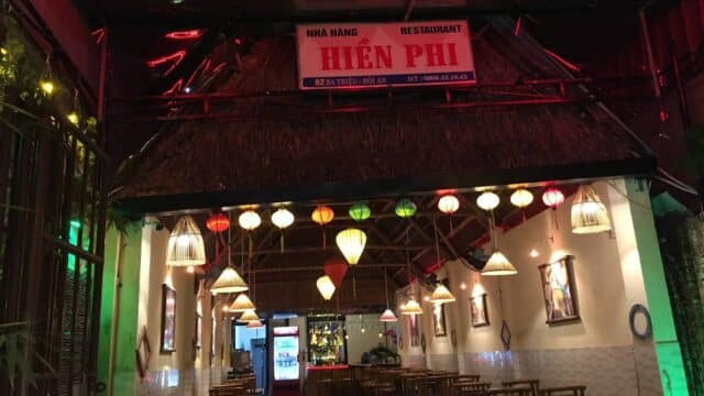 A cozy Vietnamese restaurant with bamboo chairs, hanging lanterns, and a Hoi An-inspired sign reading Hiền Phi.
