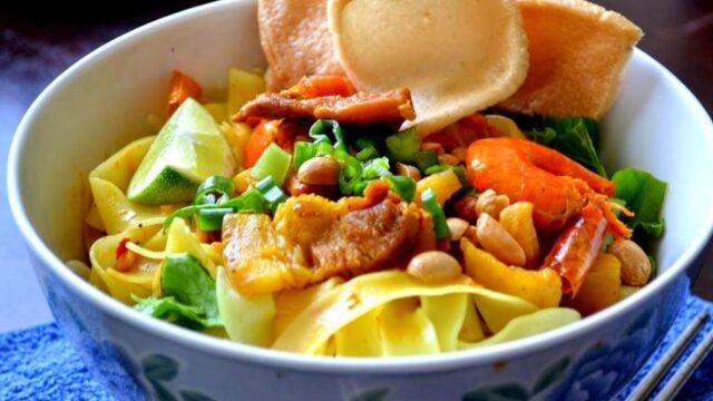 A bowl of Vietnamese noodle salad with shrimp, veggies, peanuts, and prawn crackers—a classic Hoi An street food delight.