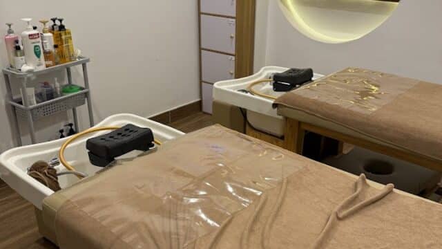 Two massage tables with brown sheets in a body spa room featuring a shelf, products, and soft, relaxing lighting.