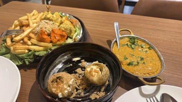 Indian meal with stuffed mushrooms, curry, fries, rice, naan, and grilled vegetables served in Hoi An on a wooden table.