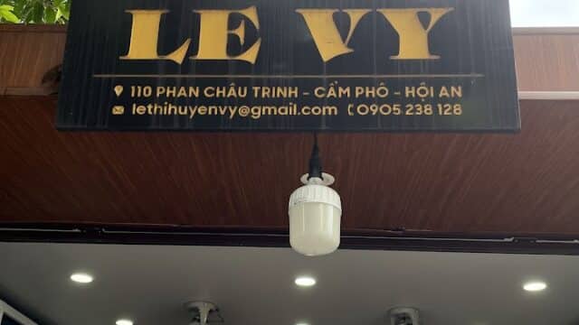 Tailor shop sign reading LE VY above a bespoke tailoring and clothing store entrance in Hoi An, Vietnam.