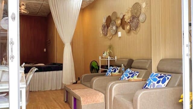 A cozy Lee Spa Nail room with reclining chairs, colorful pillows, wall decor, and a curtained massage area in the back.