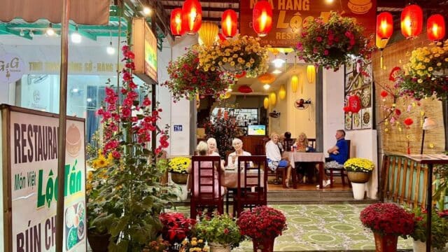 Loc Tan Restaurant: Outdoor Vietnamese dining at night, adorned with lanterns, flowers, and diners enjoying their meals.