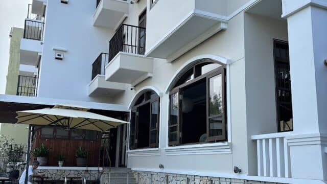 Modern Manterra Hoi An building with balconies beside a turquoise swimming pool and poolside seating under umbrellas.