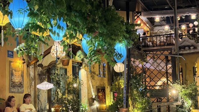 Cozy outdoor dining at Miss Van Restaurant, with blue lanterns, lush plants, and two guests enjoying dinner under warm lights.