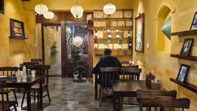 Cozy café with yellow walls, wooden tables, hanging lanterns, and a Myeongnang Hotdog on the menu for a perfect BABA moment.