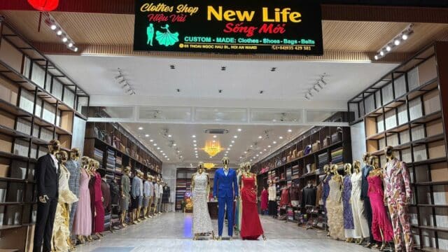 Clothing store entrance with mannequins in formal wear; shelves of fabric highlight New Life Tailor’s expert tailoring services.