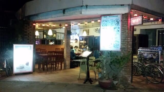 Outdoor view of a cozy Hoi An restaurant at night with people dining inside and bicycles parked outside.