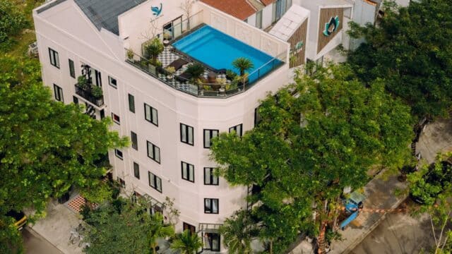 Aerial view of Quang Vinh Apartment with a rooftop pool, surrounded by trees and streets.
