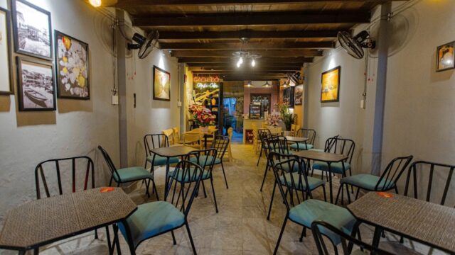 Cozy Red Brick Cafe interior with empty tables and chairs, wall art, and warm lighting leading to an inviting entrance.