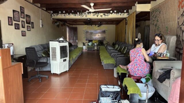 A nail salon with two women getting pedicures, surrounded by empty chairs and warm decor.