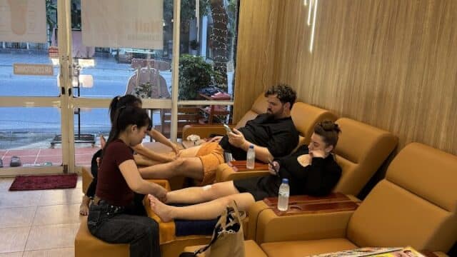 Three people relax in salon chairs while enjoying foot massages from staff at the cozy, well-lit Spring Heaven Spa.