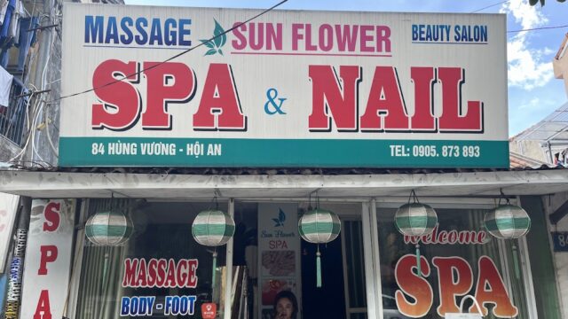 Storefront of Sunflower Spa & Nail, a welcoming nail spa with a woman at the entrance and signs for massage, spa, and nail services.