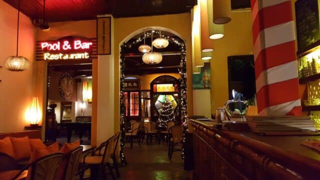 Cozy Hoi An bar and restaurant interior with warm lighting, neon sign, bamboo counter, and string lights.