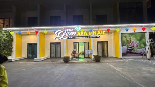 Front view of Gem Spa & Nail at night, with colorful lanterns and bright spa signage above the entrance.