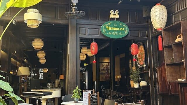 Outdoor seating at Poison Cafe, a rustic café with wooden decor, hanging lanterns, lush plants, and expertly brewed coffee.