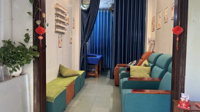 A cozy Thien Nhan Spa waiting area with teal chairs, green cushions, wall art, and blue curtains in the background.