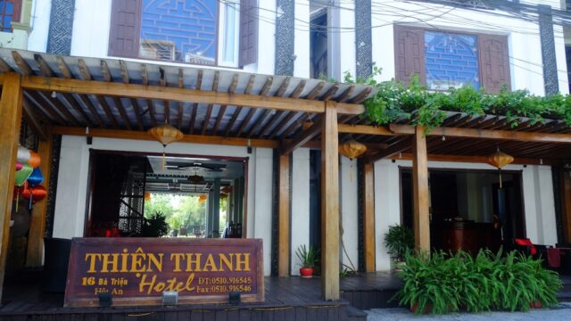 Hotel entrance with wooden patio, lanterns, plants, and a sign reading Thien Thanh Boutique Hotel in Vietnamese.