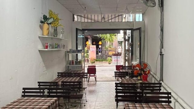 Small, cozy Hoi An cafe with checkered tablecloths, simple decor, and an open entrance facing the street.