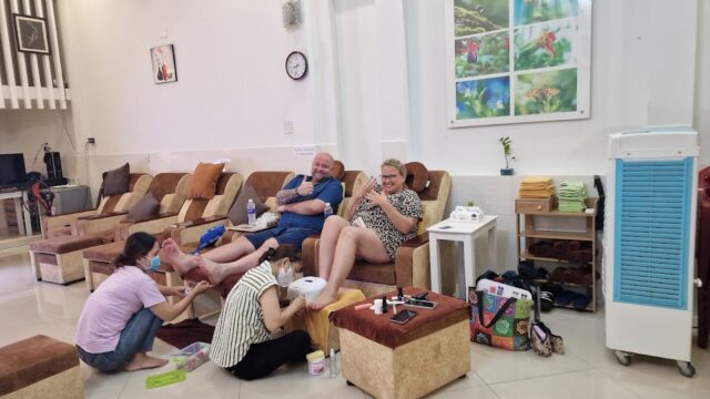 Two people enjoy pedicures from staff at Tigon's House Spa, a bright, modern nail salon with comfy chairs.