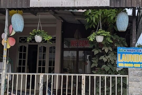Entrance of Toms Spa with plants, hanging pots, and a “laundry” sign outside the gate.