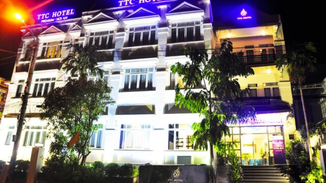 TTC Hotel building in Hoi An brightly lit at night with neon signs and an illuminated entrance.