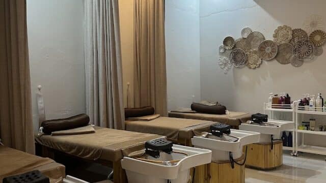 Four spa beds with foot soak tubs in a serene, softly lit room with beige curtains and wall decor.