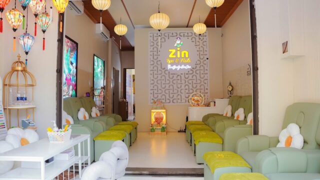 Bright, cozy Zin Spa interior with green chairs, daisy pillows, and lanterns hanging from the ceiling.