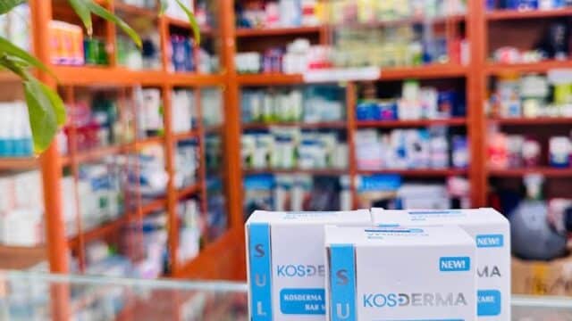 Boxes of Kosderma sulfur soap on a pharmacy counter in Hoi An, with an ABC Pharmacy business card in front.